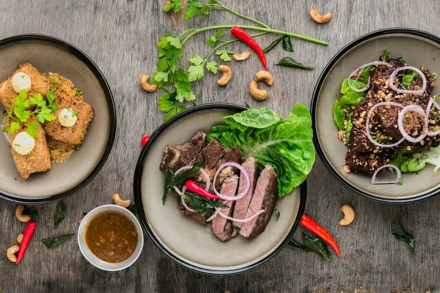 Freshly prepared plates with herbs, meat and salads on a rustic table